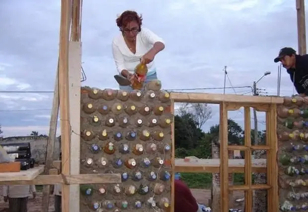 Femme bâtie maison de bouteilles en plastique