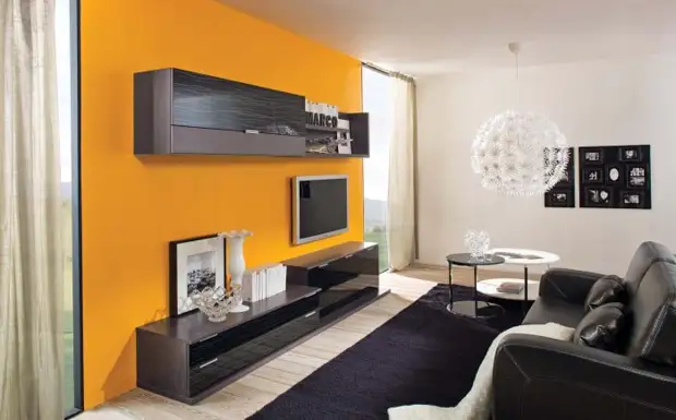 A zona para visualizar a TV é destacada com papel de parede amarelo contrastante, que são destacados no interior da sala de estar.