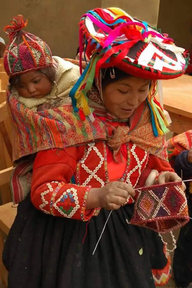 مادر Andean Knitter و بافندگی با بچه در پشت، پوشیدن CHULLO دستبند دستبند ~ پرو